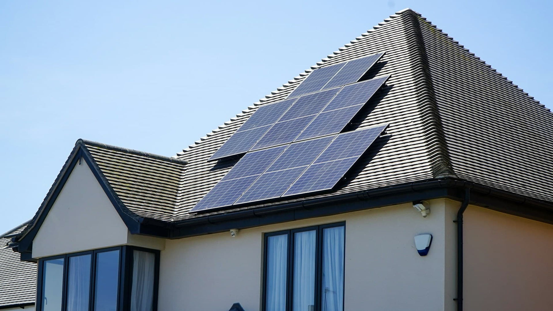 Solar panels on a roof with security cameras below ensuring a secure property